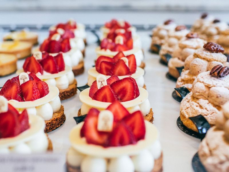 Variety of gourmet pastries topped with fresh strawberries and cream, neatly arranged on a display.