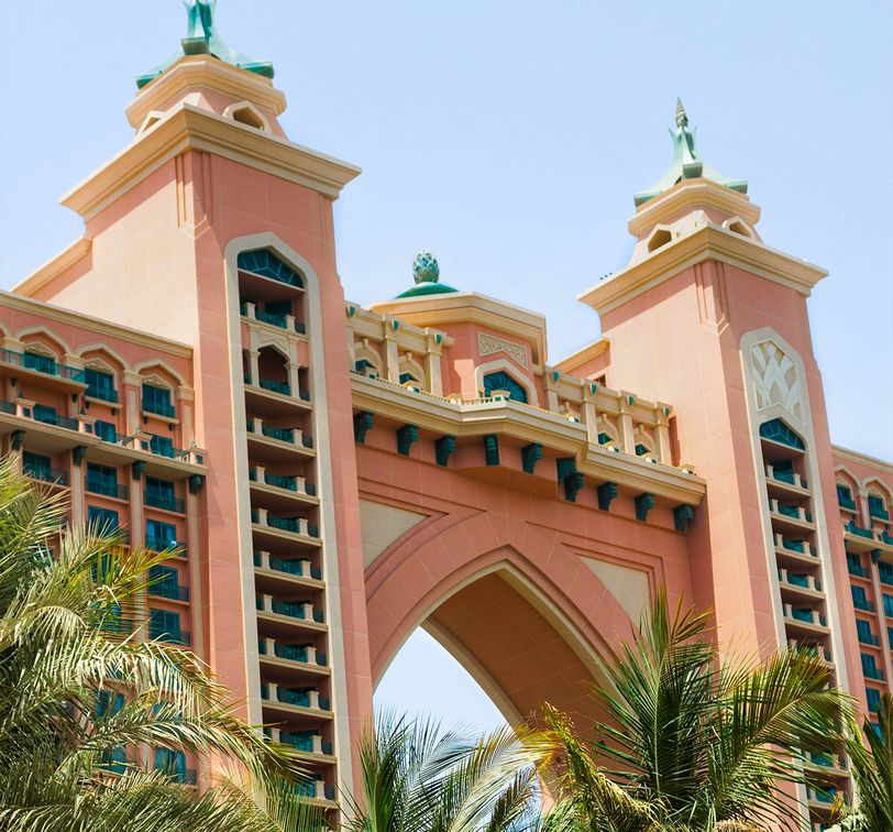A pink hotel with a large arch surrounded by palm trees in Dubai, United Arab Emirates