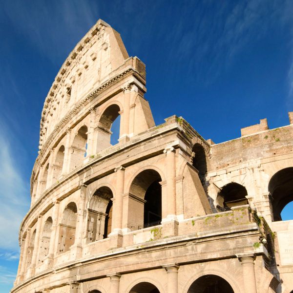 The Colosseum under a clear blue sky, showcasing its arched structure and weathered stone façade.