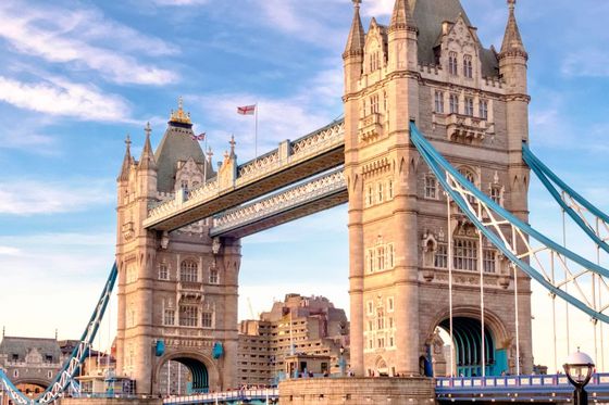 Tower Bridge in London with a clear blue sky, featuring its two distinct towers connected by a suspended walkway.