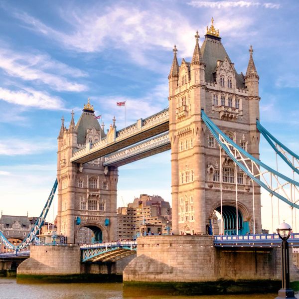 Tower Bridge in London with a clear blue sky, featuring its two distinct towers connected by a suspended walkway.