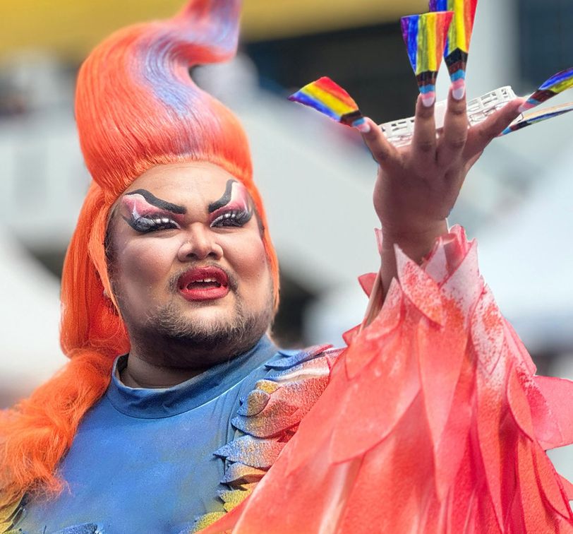 A person with orange hair and a colorful wig at Bangkok Pride Parade.