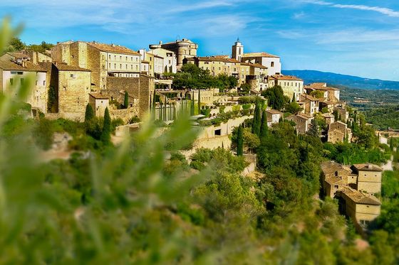 A city on a hill with trees in the foreground.
