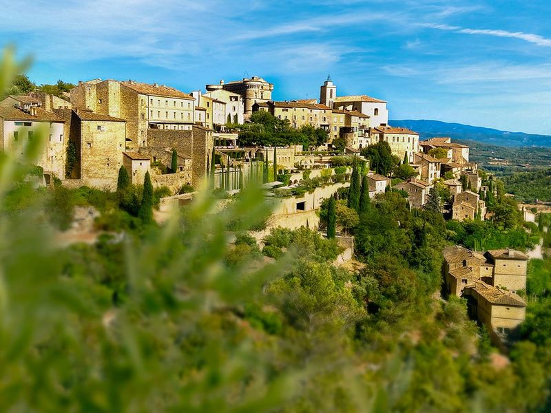 A city on a hill with trees in the foreground.