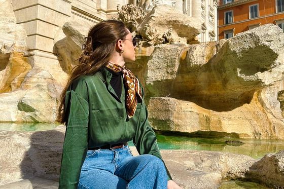 A woman sitting on the edge of the Trevi Fountain