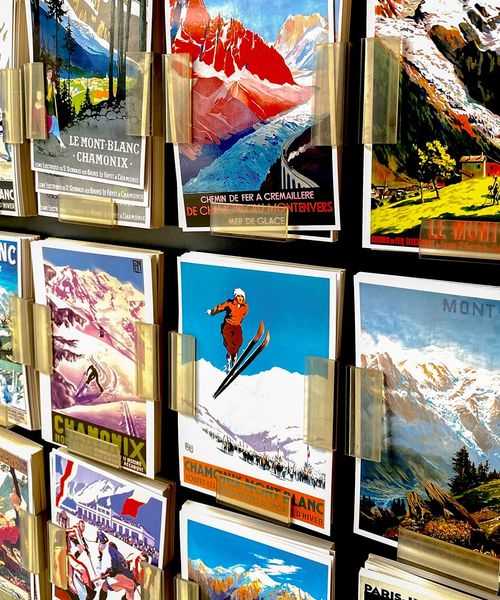 A display of colorful vintage Mont-Blanc ski postcards with scenic mountain images and skiers, held in clear plastic holders on a stand.
