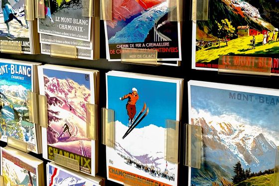 A display of colorful vintage Mont-Blanc ski postcards with scenic mountain images and skiers, held in clear plastic holders on a stand.