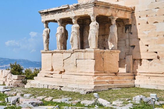 The Erechtheion with six Caryatid statues on the Acropolis in Athens, Greece, under a clear blue sky.