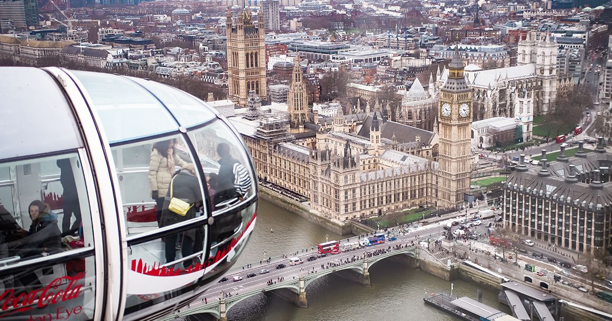 Aerial view of the London Eye capsule with passengers, overlooking the Houses of Parliament, Big Ben, and Westminster Bridge.