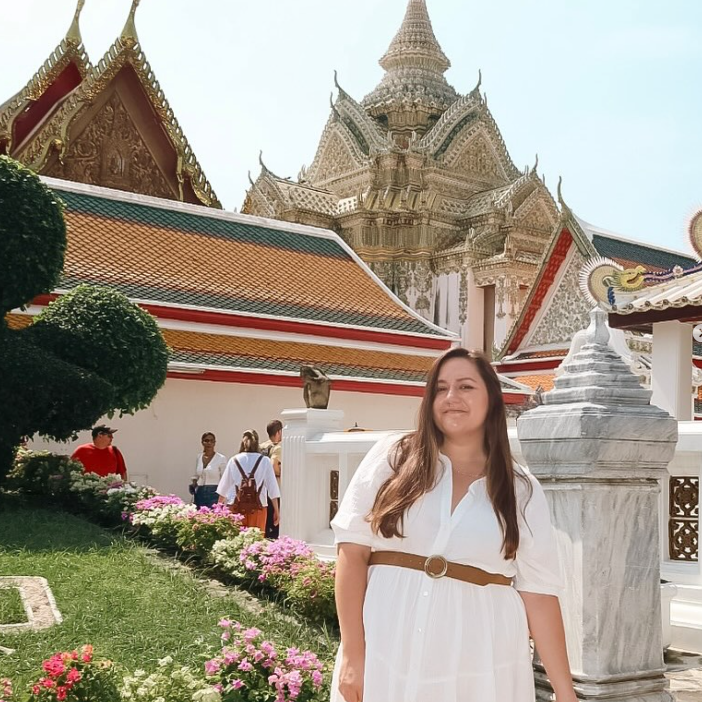 Woman posing in front of an ornate, colorful temple in Thailand