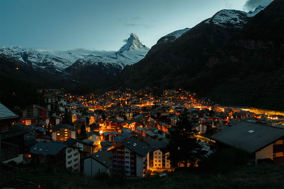 A city lit up at night with mountains in the background