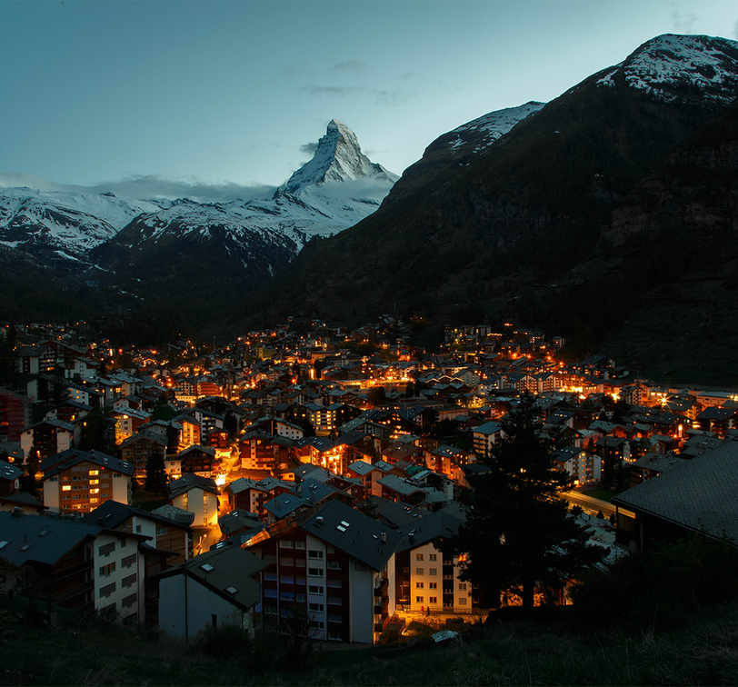 A city lit up at night with mountains in the background