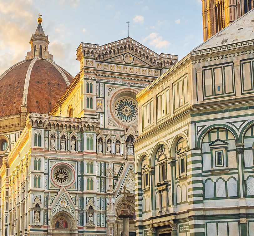 The Florence Cathedral, with its intricate facade and large dome, is bathed in warm sunlight against a clear sky.
