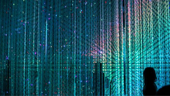 Silhouette of a person standing against a backdrop of cascading colorful LED lights, creating a vibrant, immersive visual display.