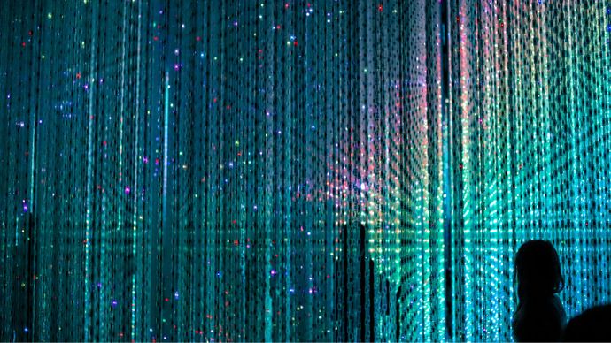 Silhouette of a person standing against a backdrop of cascading colorful LED lights, creating a vibrant, immersive visual display.