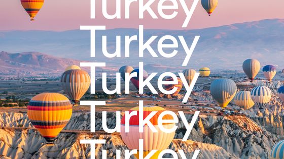 Colorful hot air balloons float over Cappadocia's unique rocky landscape at sunrise, with the word "Turkey" repeated prominently.