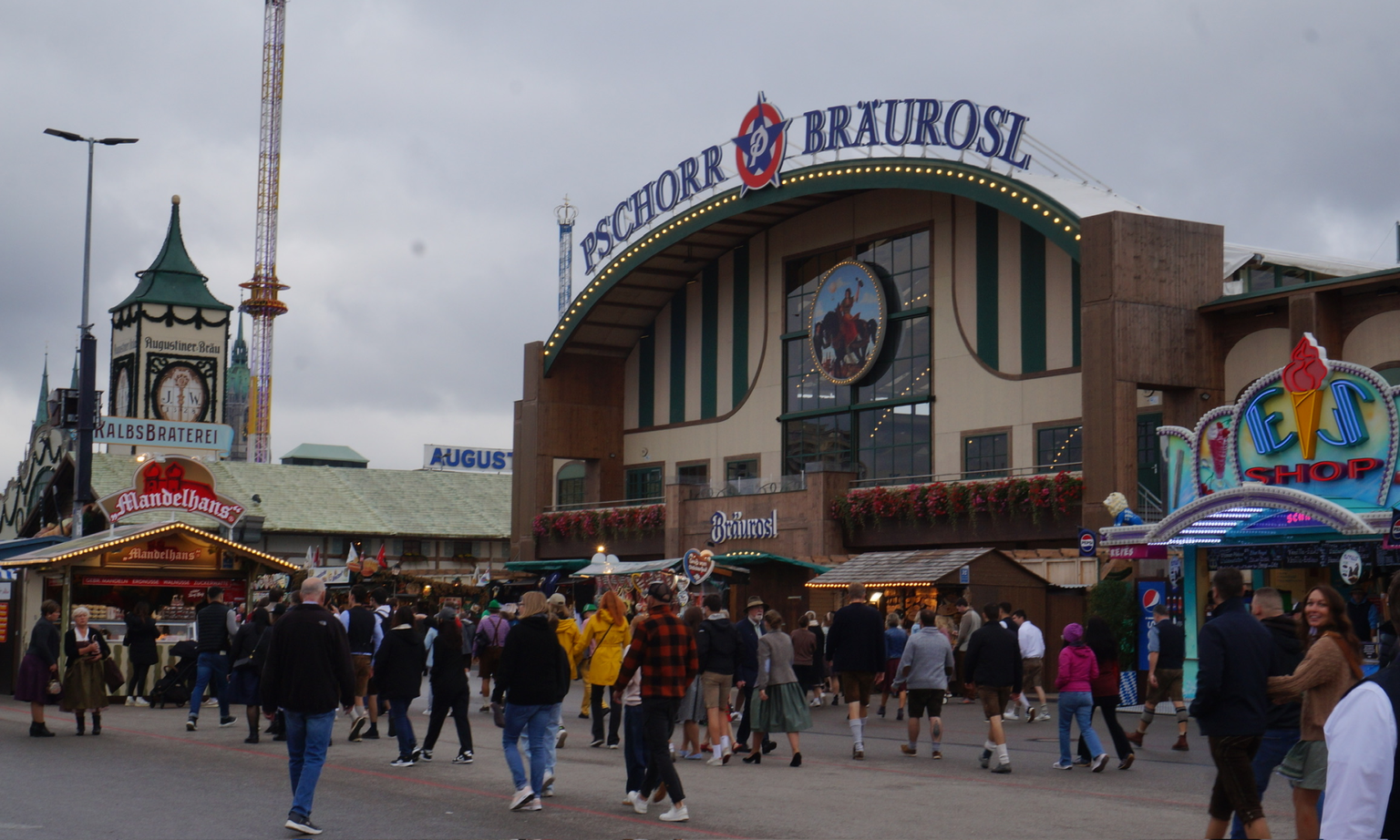 Outside of the Pschorr-Bräurosl Oktoberfest tent with vendors and people walking around in front.