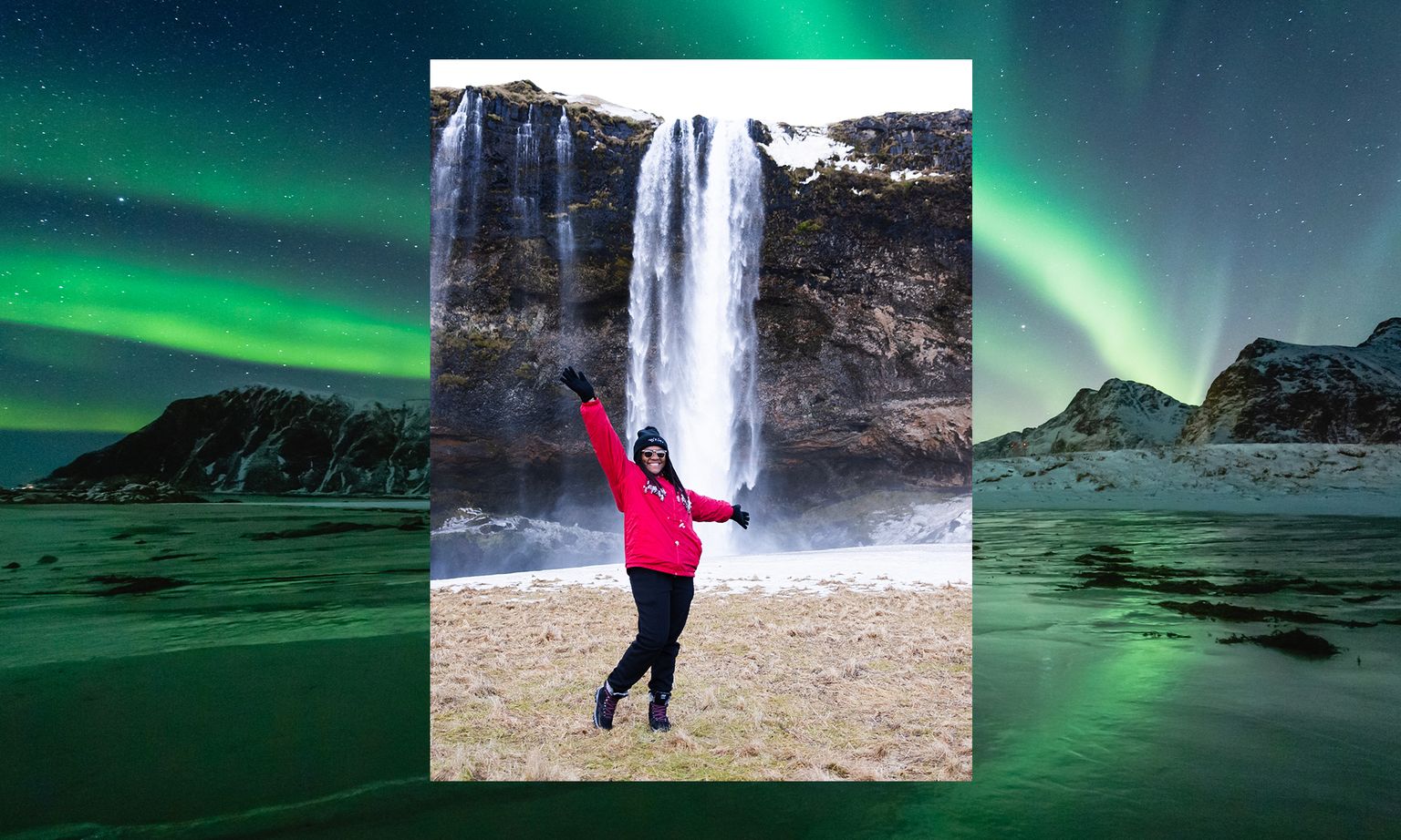 Person in a red jacket poses joyfully in front of a waterfall, with vibrant northern lights illuminating the snowy landscape behind.
