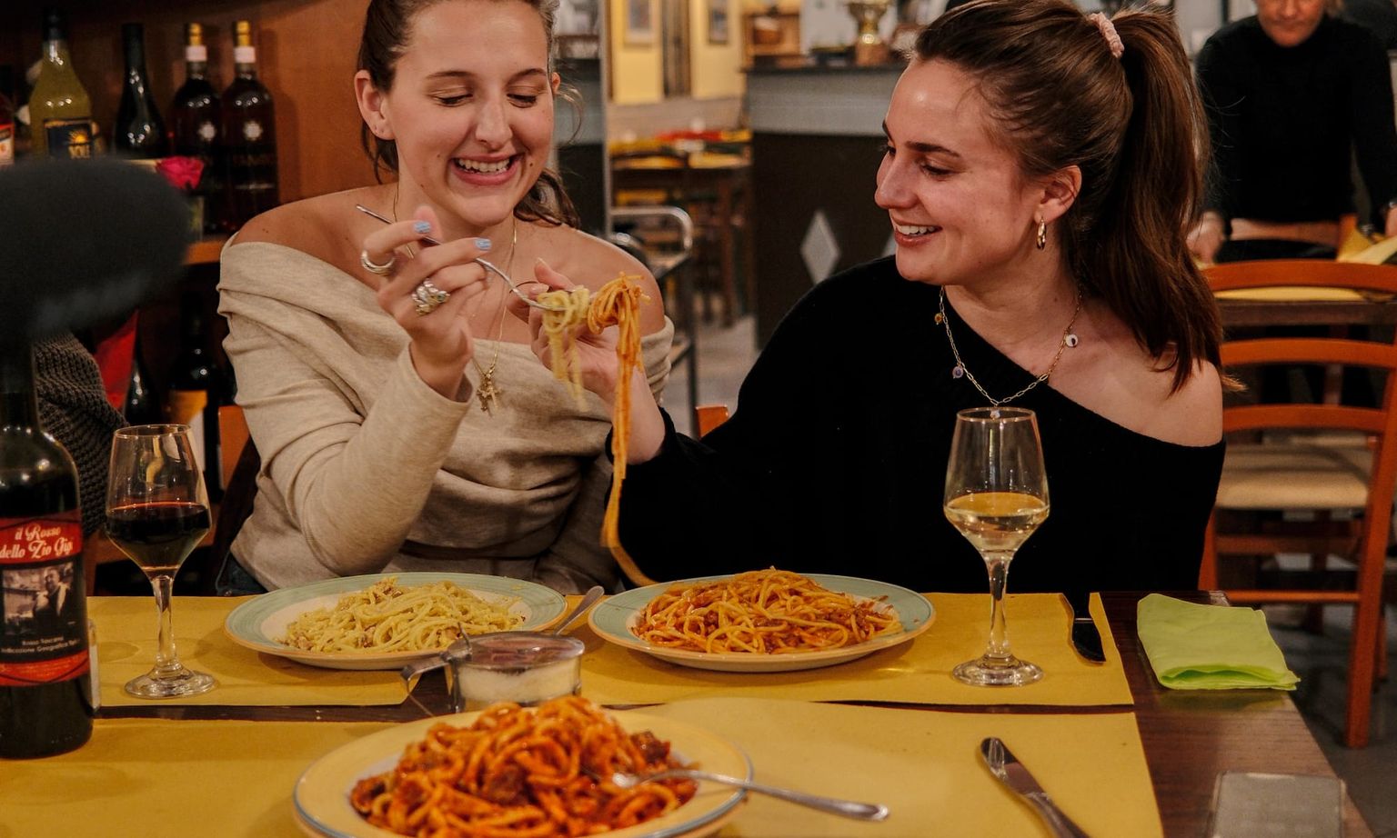 Two women eating pasta and drinking wine at a table in Florence, Italy