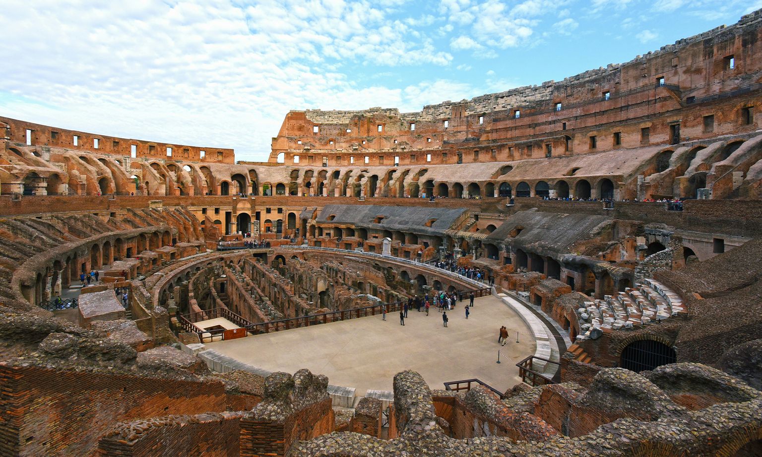 People walking around the ruins of the Colosseum's amphitheater in Rome, Italy