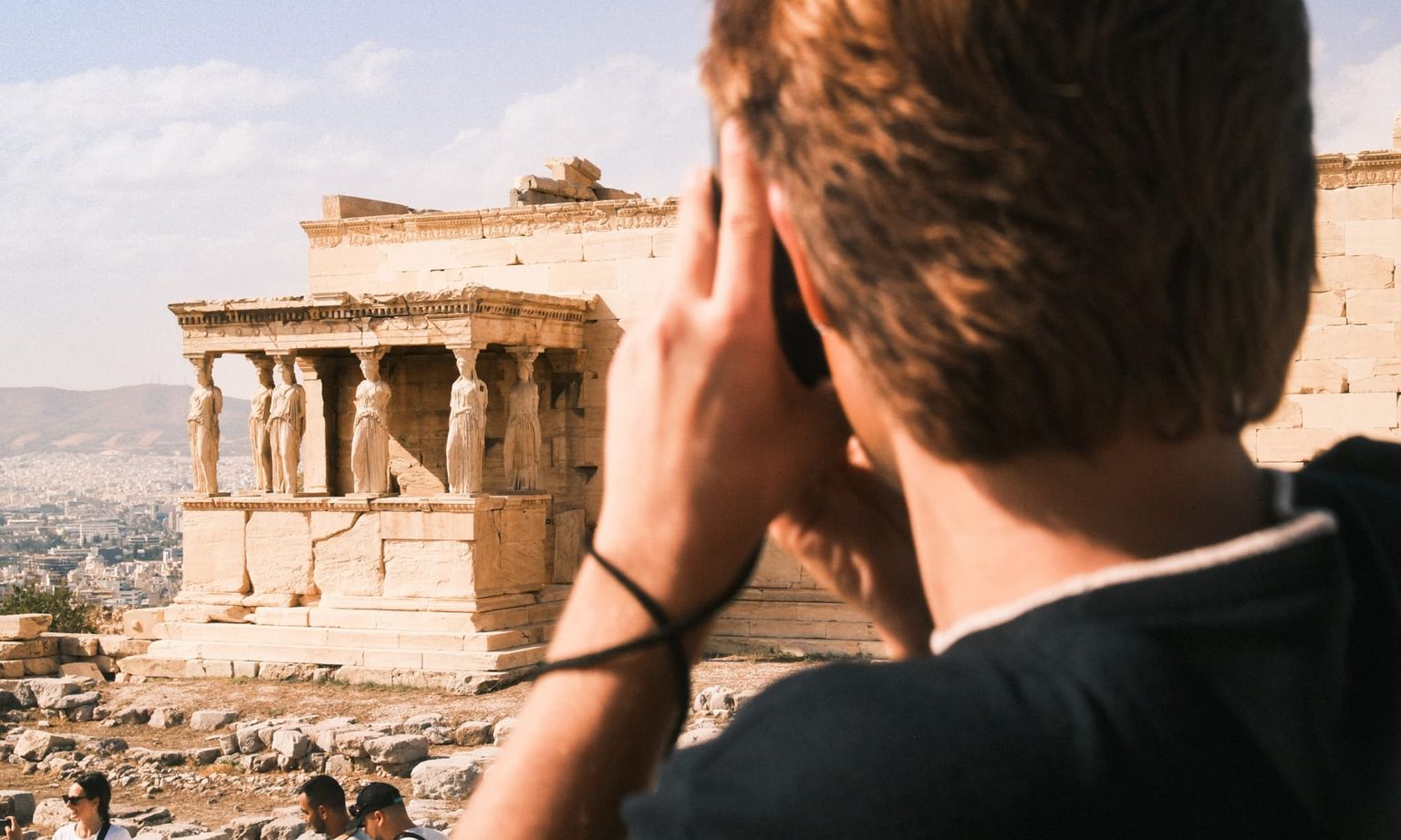 A person taking a photo of ancient ruins at the Acropolis in Athens, Greece