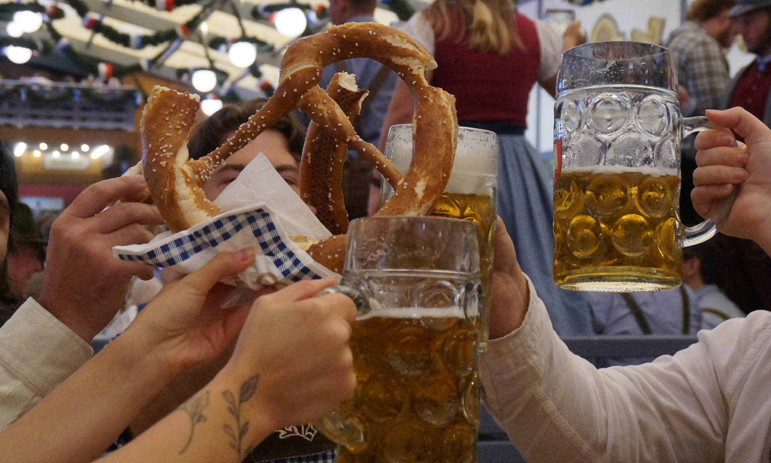 A group of people clinking their steins and pretzel together.