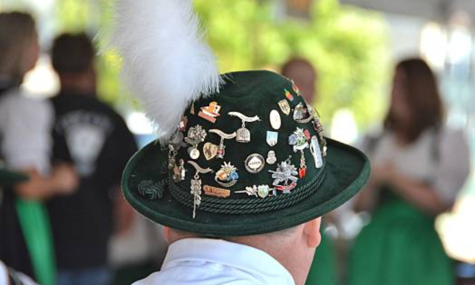 A man in a green hat filled with pins and a feather.