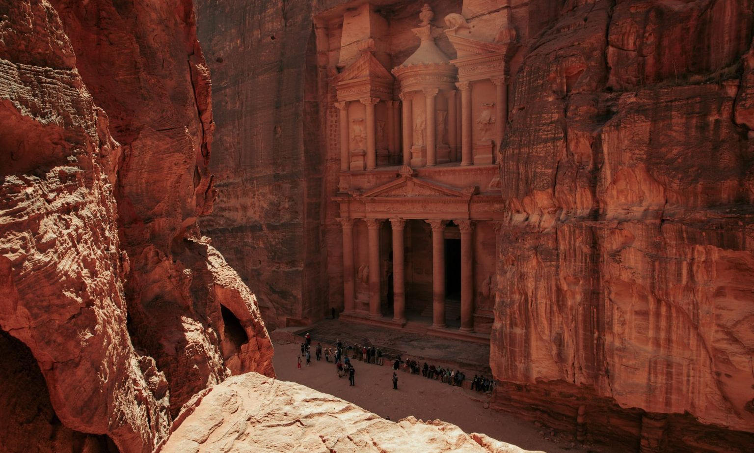A group of people gathered at the base of the ancient stone city of Petra in Jordan