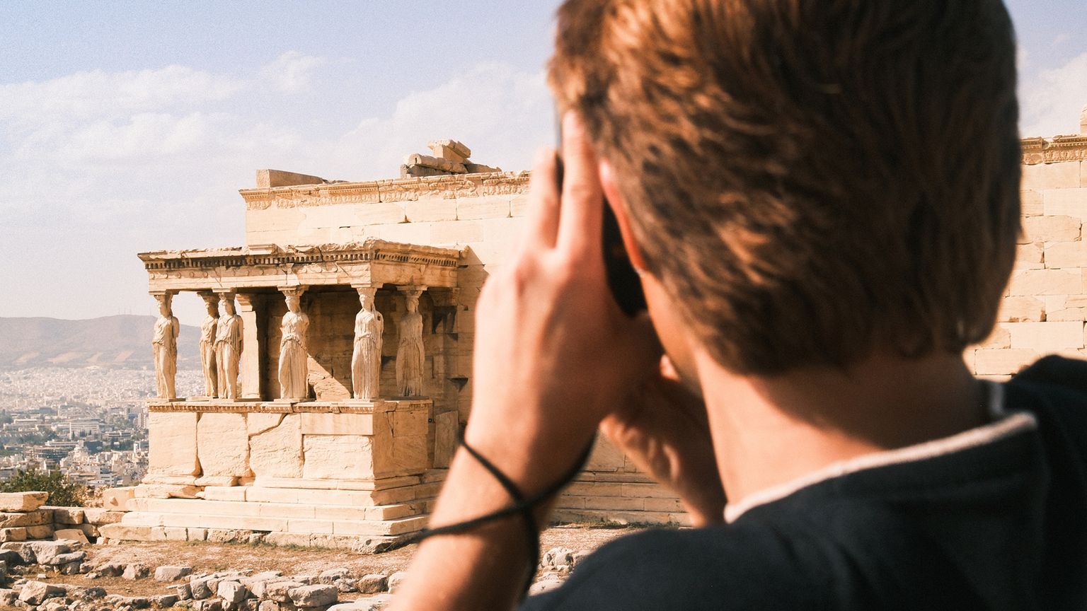 A person taking a photo of ancient ruins in Athens, Greece