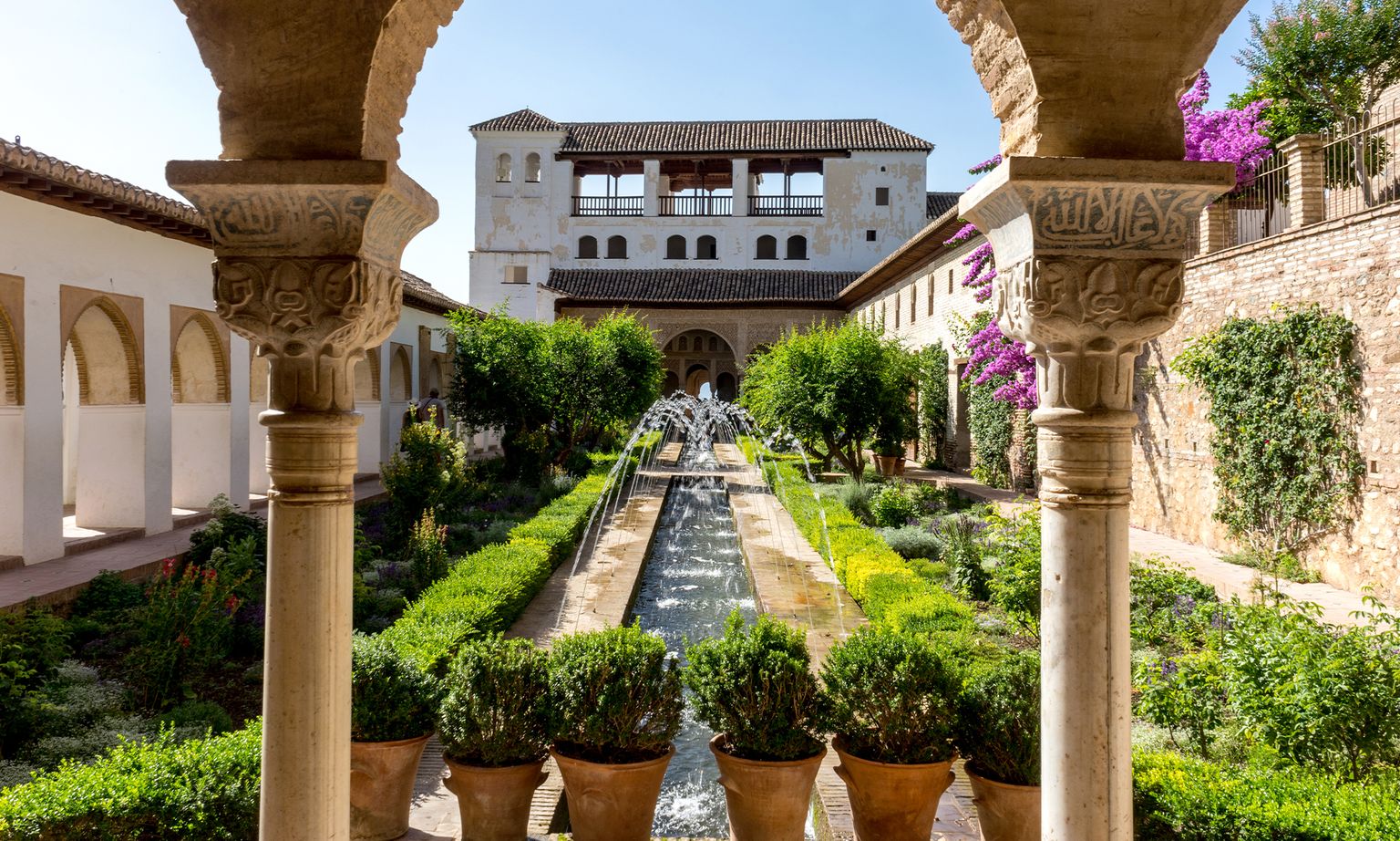 Outside in the green, flowering Generalife Gardens within Alhambra fortress in Granada, Spain.