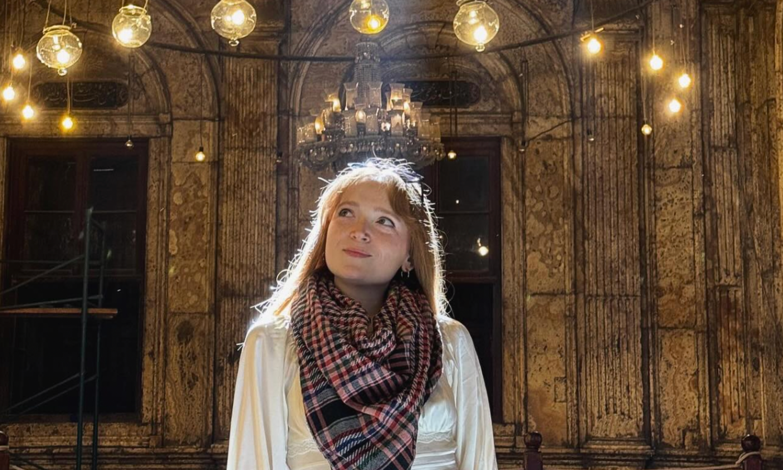 A woman in a scarf smiling in a temple.