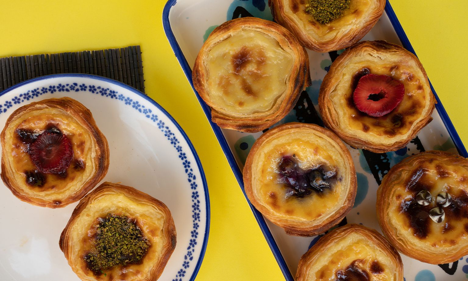 Various custard pastries on plates atop a colorful yellow table