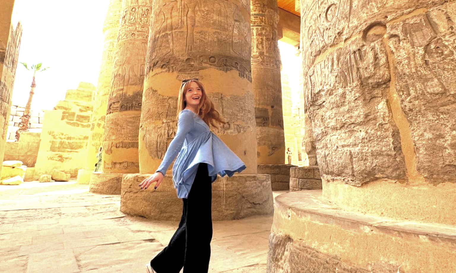 A woman twirling under Egyptian columns.