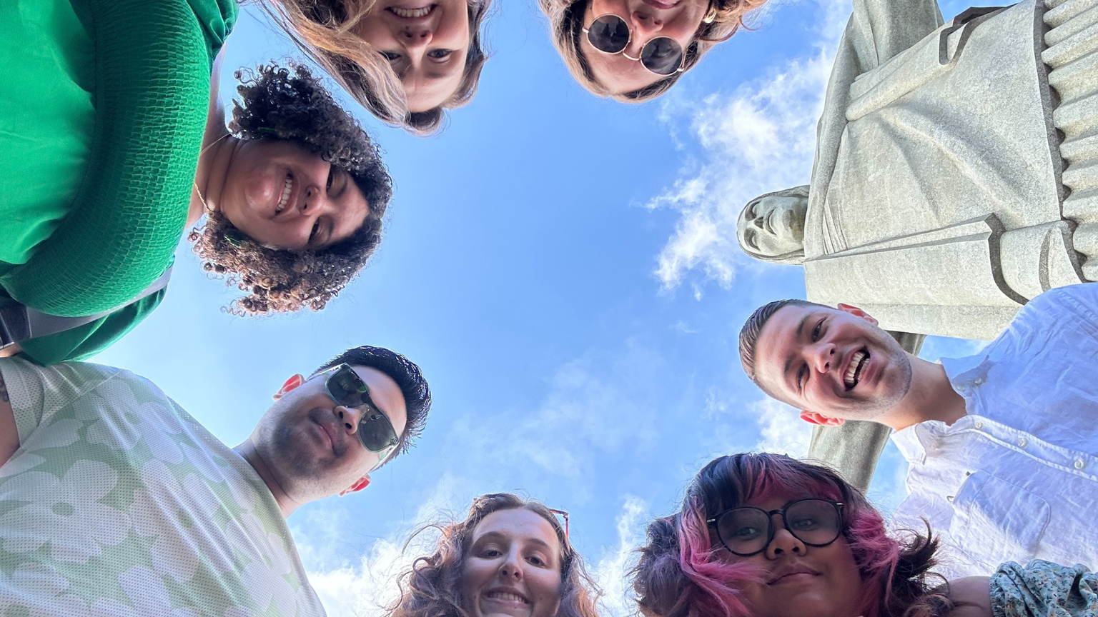 A group of people standing in a circle with Christ the Redeemer statue.