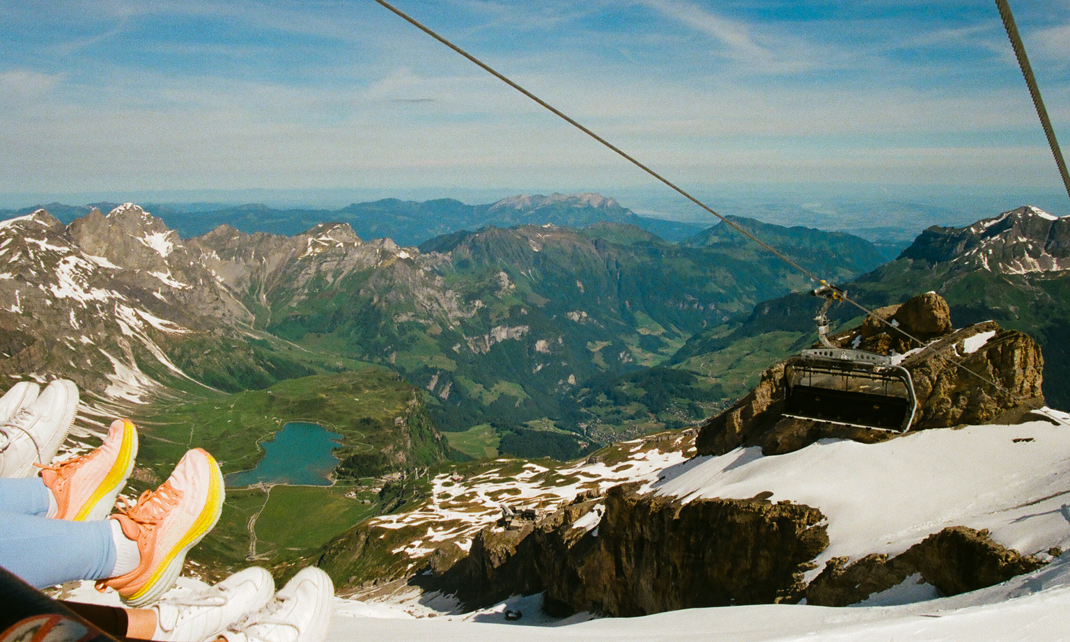Three people's feet peeking off a cable car from Mount Titlis in the Swiss Alps