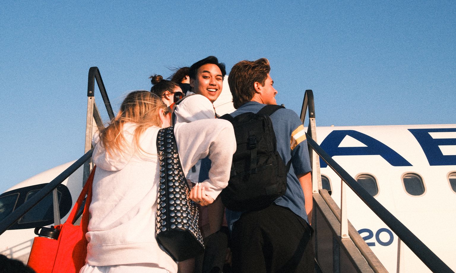A group of people walking up a staircase to board a plane