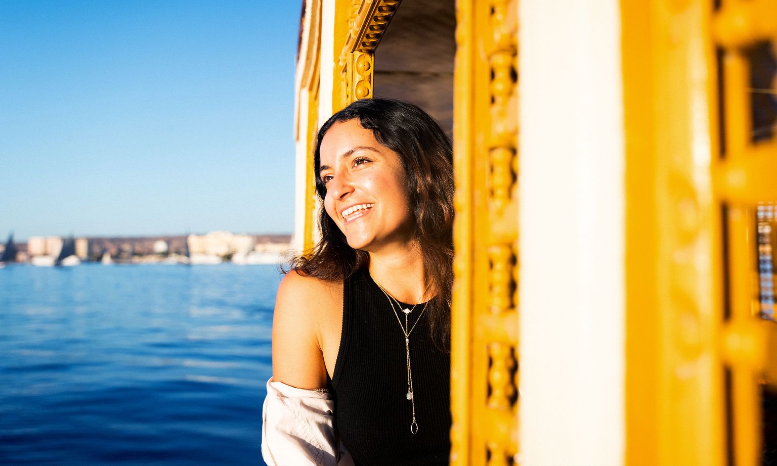 A woman looking out at the sea from the window of a ship.