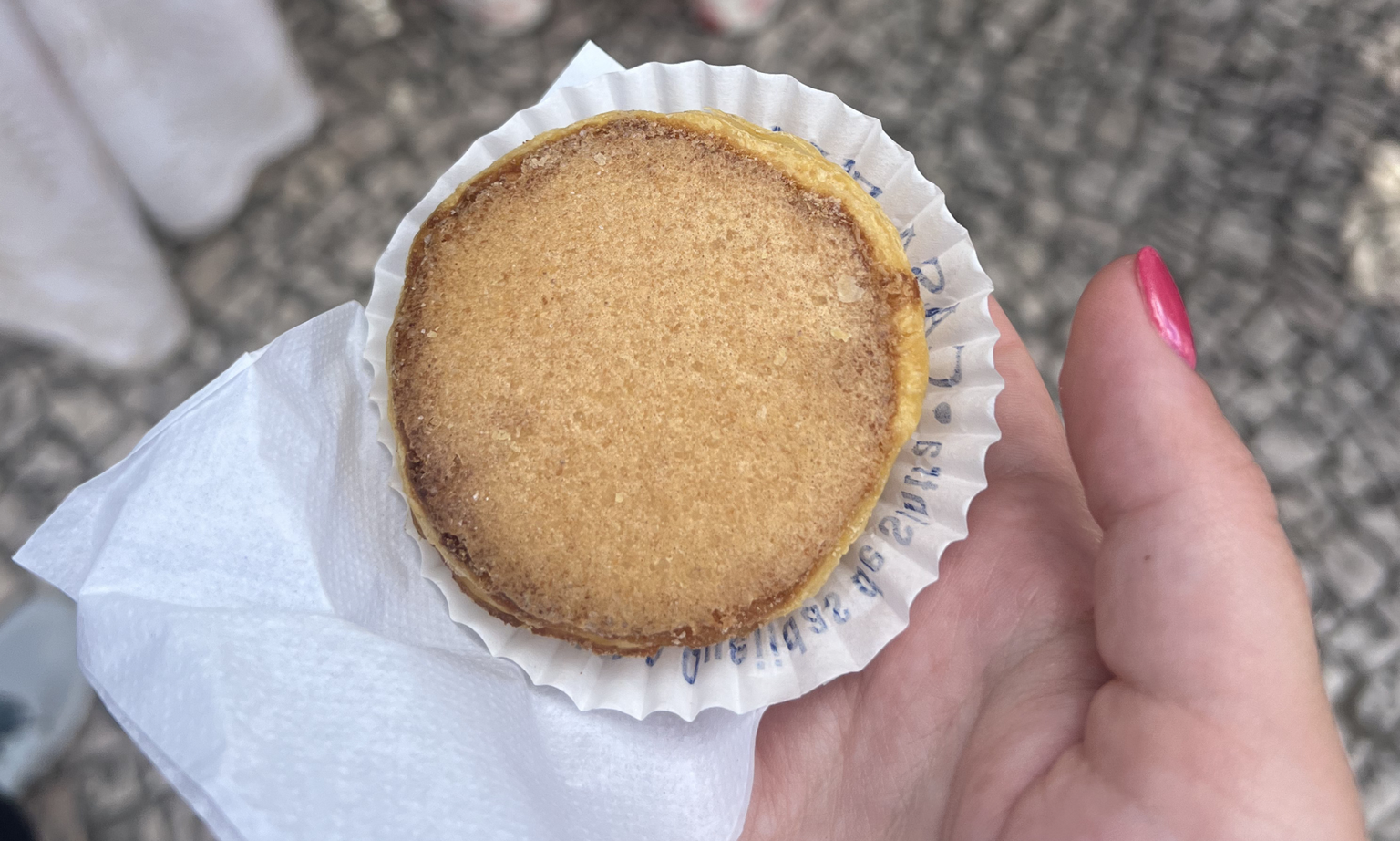 An overhead photo of a hand holding a Portuguese custard pastry called a pasteis de nata