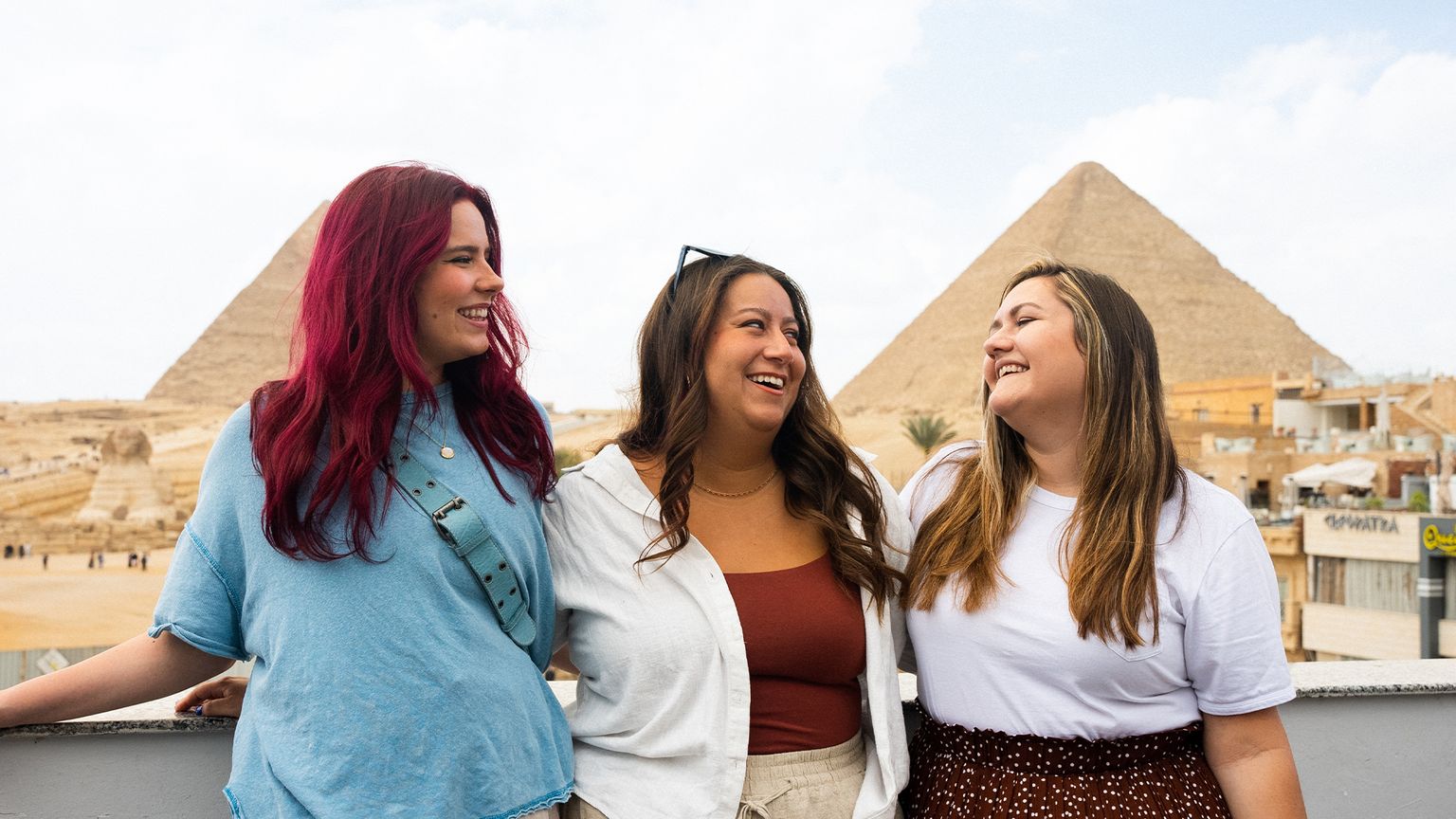A group of women smiling and posing in front of the pyramids.