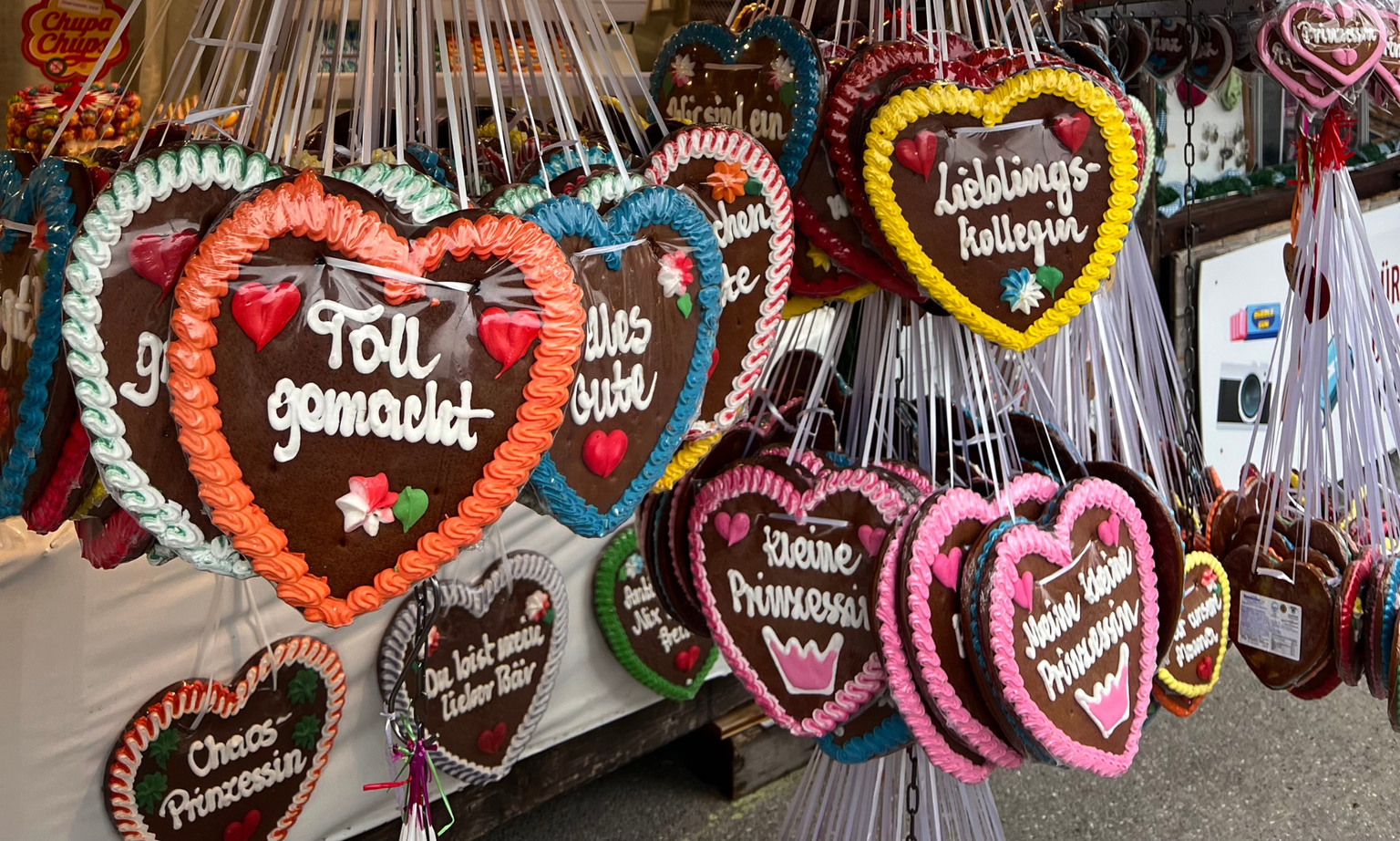 Close-up of multiple Lebkuchenherz cookies and their German sayings.