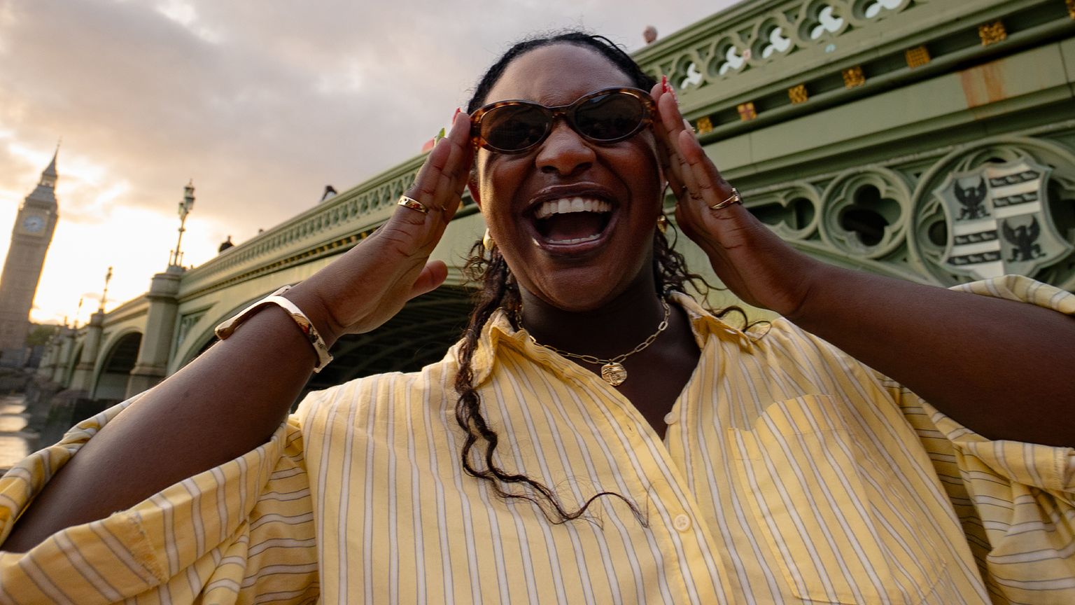 Woman posing with sunglasses in front of Westminster Bridge and Big Ben in London.