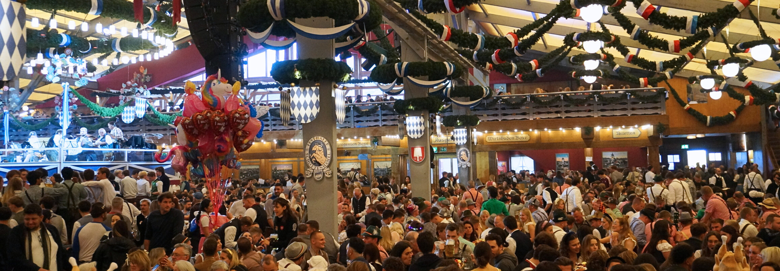 Inside an Oktoberfest beer tent filled with crowds of people.