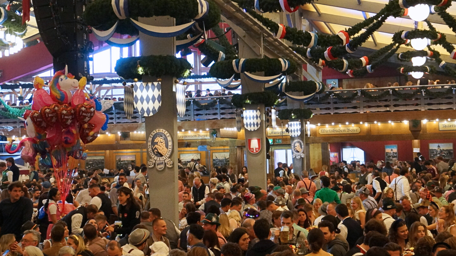 Inside an Oktoberfest beer tent filled with crowds of people.