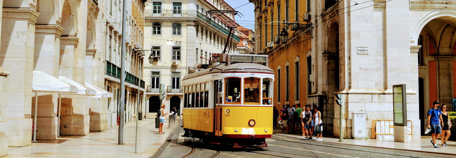 A yellow trolley driving down an old Portuguese street.