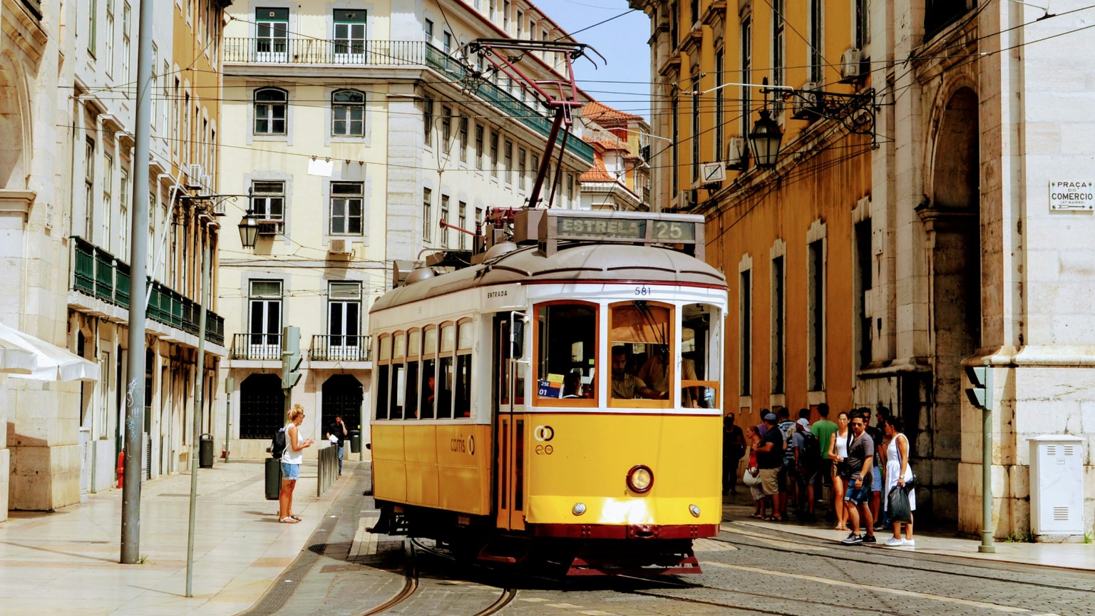 A yellow trolley driving down an old Portuguese street.