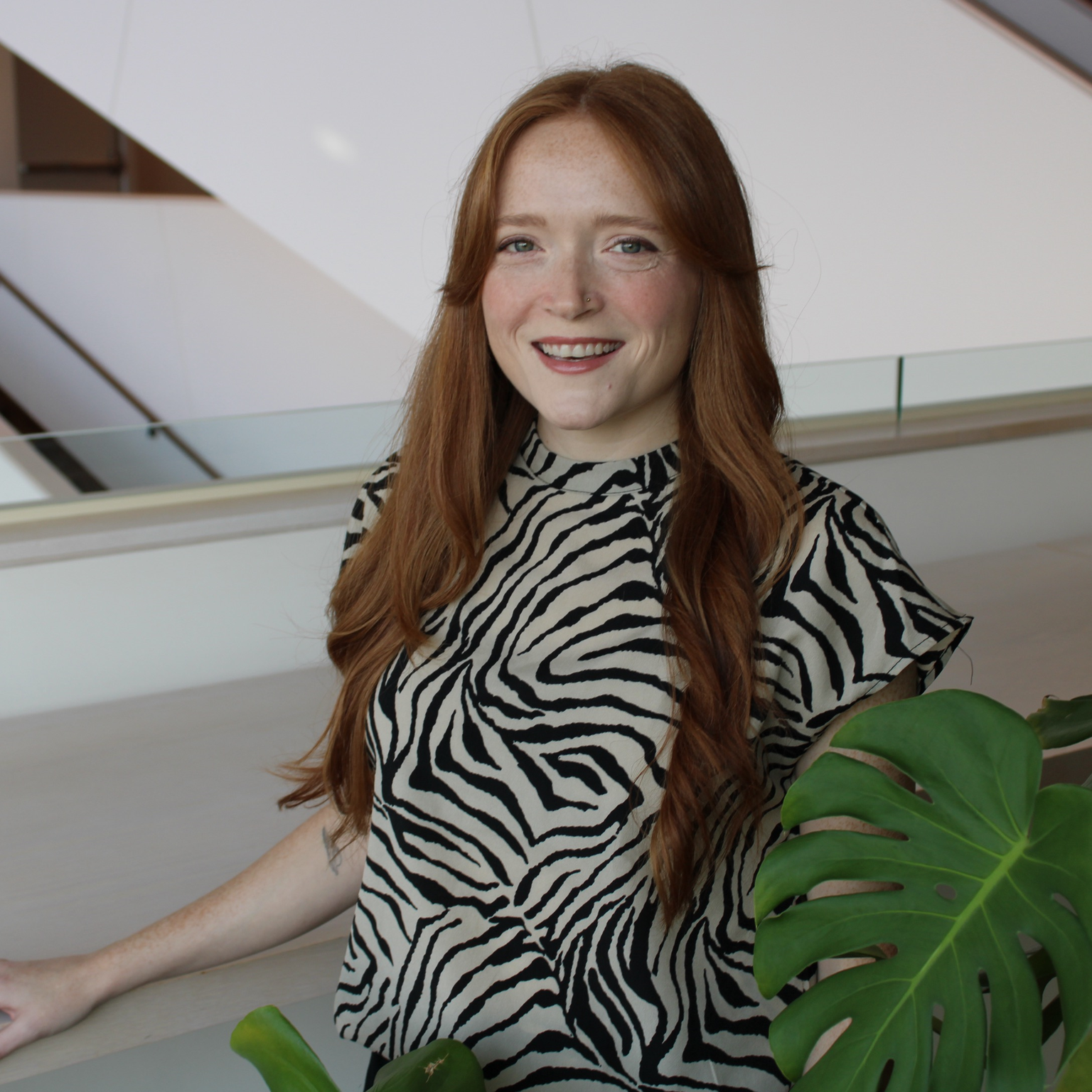 A woman posing with a monstera plant