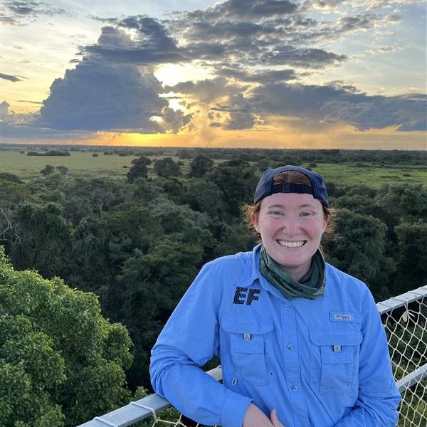 A woman standing on a balcony overlooking a jungle