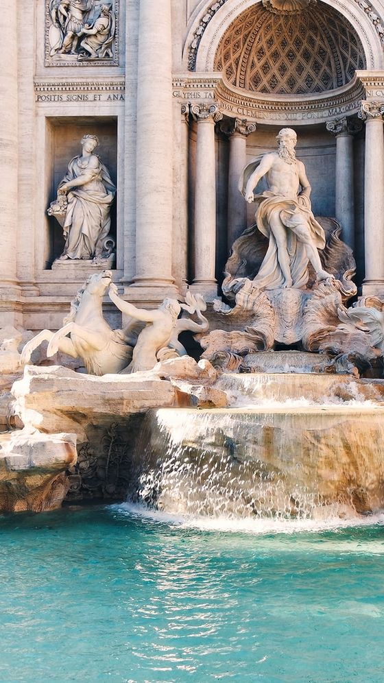 The Trevi Fountain in Rome, featuring ornate sculptures and flowing water cascading into a clear blue pool.