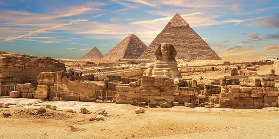 The image shows the Sphinx and Pyramids of Giza under a vibrant sky, with ancient ruins in the foreground.