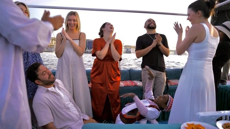 A group of people laughing on a boat floating on the Nile River at sunset